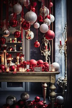 red and white ornaments are hanging from the ceiling above a table with candles on it