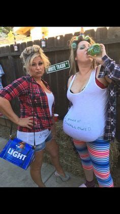 two women dressed in costumes standing next to each other near a fence and eating food