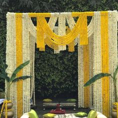 an outdoor wedding setup with yellow and white flowers, greenery, and tables set up for the ceremony