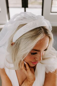 a woman with blonde hair wearing a white headband that says bride on the side