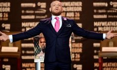 a man in a suit and tie standing on stage with his hands out to the side