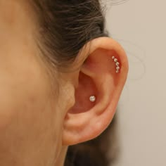 a close up of a person's ear with three small diamond studs on it