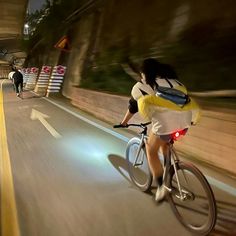 a woman riding a bike down a street at night