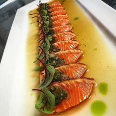 a white plate topped with sliced salmon and sauce