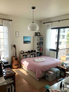 a bed room with a neatly made bed and a guitar on the desk next to it