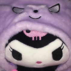 a close up of a stuffed animal wearing a purple outfit with black and white stripes