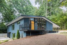 a blue house in the woods with stairs leading up to it's second floor