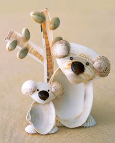 two teddy bears are sitting on top of a surfboard with seashells around them