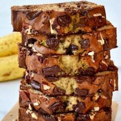 a stack of chocolate chip banana bread on a cutting board with two bananas in the background