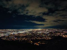 the city lights are lit up at night from atop a hill in this aerial view