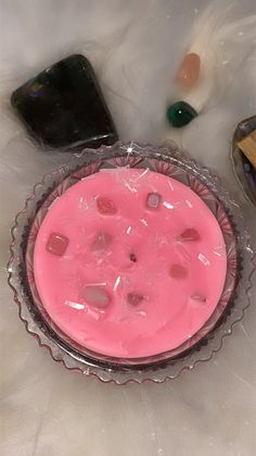 a pink substance in a glass bowl next to other items on a white tablecloth