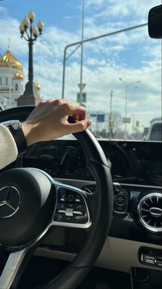 a person driving a car on a street with buildings in the background