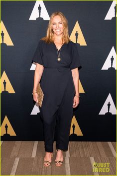 a woman in black jumpsuits standing on the red carpet at an oscar awards event