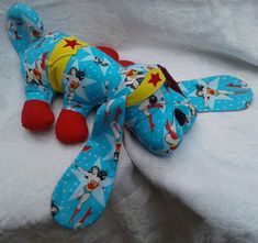 a blue stuffed animal laying on top of a white sheet