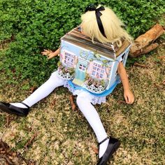 a doll sitting in the grass with a box on it's head and legs