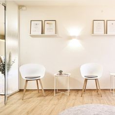 two white chairs sitting next to each other on top of a hard wood floored floor