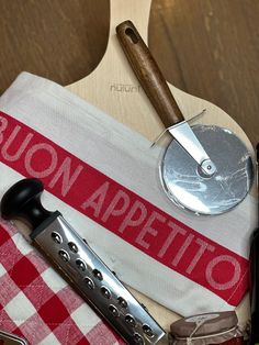 an assortment of kitchen utensils and wine on a picnic tablecloth with a wooden spatula