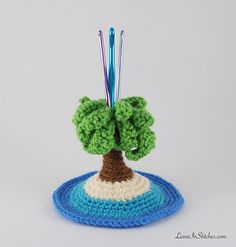 a small crocheted tree on top of a blue and white plate with needles in it