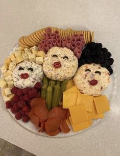 a white plate topped with cheese, crackers and vegetables covered in faces on it