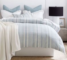 a bed with blue and white striped comforter in a bedroom next to a lamp