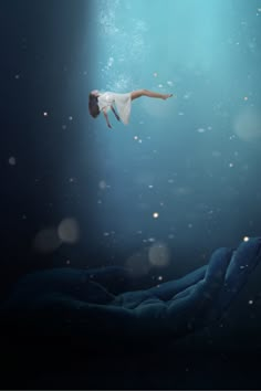 a woman floating in the air with her arms outstretched and feet spread out, under water