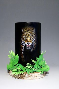 a black coffee mug with a leopard on it's face surrounded by green leaves