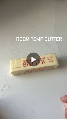 a person holding a bar of butter on top of a white surface with the text room temp butter