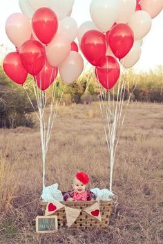 a baby sitting in a basket with balloons