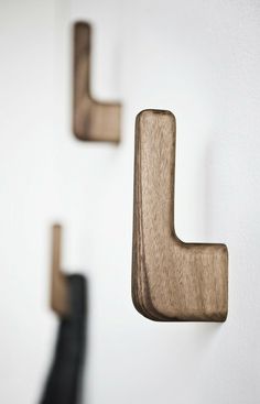 three wooden hooks mounted to the side of a wall