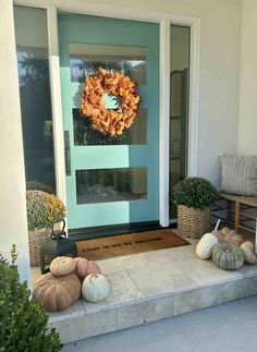 a front porch with pumpkins and a wreath on the door sill next to it