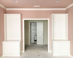 an empty room with pink walls and white trim on the doors, shelves and cabinets