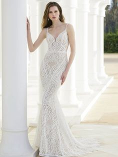 a woman in a white wedding dress standing next to columns