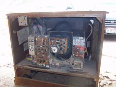 the inside of an electrical box with wires and other equipment in it on concrete area next to parked car