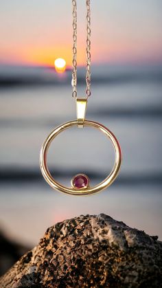 Feel fabulous in this solid 9ct yellow gold and ruby circular pendant.  Named the 'Oriana Rose', meaning Golden Sunrise, this pendant shimmers and shines around your neck, evoking a real festive feel. Symbolising the circle of life in a year, the Oriana Rose is an ideal Valentine's Day gift. The ruby is a rich and vibrant red; red being the colour of  love and glints beautifully in its rub over setting. You don't need to worry about buying the correct size; this pendant fits all and has a clip on bail so you can wear it with or without the bail and includes the chain photographed. So why do you need this pendant?  A ring might not be the exact message you want to convey and bracelets are tricky to size as well. This pendant is on trend, but is unique in its design. My silver and gold penda Ruby Round Pendant Necklace, Round Ruby Birthstone Necklace, Ruby Birthstone Necklace With Round Gemstone, Ruby Gemstone Birthstone Necklace, Ruby Necklace With Polished Yellow Gold Finish, Yellow Gold Ruby Necklace, Yellow Gold Ruby Necklace With Polished Finish, Ruby Round Pendant Necklace Hallmarked, Gold Ruby Round Jewelry