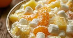 a bowl filled with oranges and marshmallows on top of a wooden table