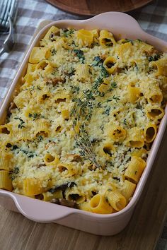 a casserole dish with pasta, cheese and herbs in it on a table