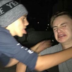 two young men sitting next to each other with one holding the other's head