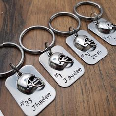 four personalized metal keychains with helmets on them, one for each person