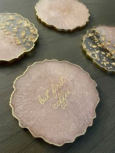 three pink and gold plates with writing on them sitting on a wooden table next to each other