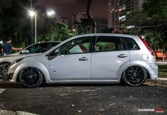 two small cars parked next to each other on the side of a road at night