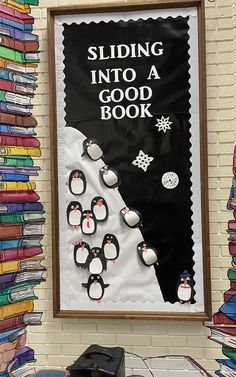 a bulletin board with penguins and snowflakes on it next to a pile of books