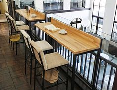 an empty restaurant with wooden tables and bar stools on the second floor looking out onto the street