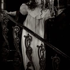 a woman in a long white dress holding a candelabra