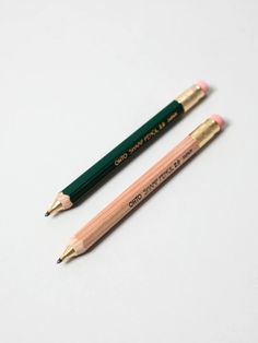 two pencils sitting next to each other on a white surface