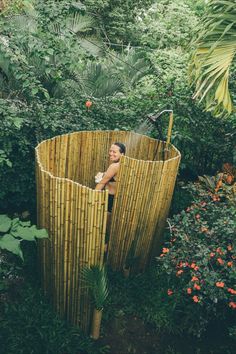 a woman standing in the middle of a bamboo structure surrounded by trees and bushes,