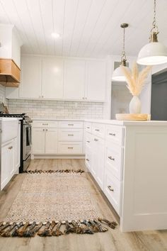 a kitchen with white cabinets and an area rug on the floor in front of the stove