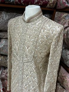 This beige white royal sherwani is brought into limelight with fine jaal embroidered coat enhanced with resham, pearl ,stone & cut dana work. The coat is styled with matching churidar pants. Size:40,42,44 Occasion: Wedding Ceremony or Reception WASH CARE INSTRUCTIONS - Please Dry clean only when it is applicable. Slight color variation is possible due to digital photography. Ready to Ship! Elegant Raw Silk Sherwani With Intricate Embroidery, Raw Silk Sherwani With Naqshi For Reception, Eid Raw Silk Sherwani With Intricate Embroidery, Eid Sherwani With Intricate Embroidery In Raw Silk, Naqshi Bandhgala In Jamawar For Reception, Traditional Cream Sherwani With Embroidery, Festive Beige Sherwani With Intricate Embroidery, Elegant Raw Silk Bandhgala With Intricate Embroidery, Traditional Cream Embroidered Sherwani