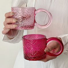 a woman holding a pink glass mug in her hands