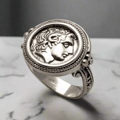 This unique Alexander the Great Portrait Coin Ring in Sterling Silver is perfect for those with a deep appreciation for ancient Greek jewelry. Finely handcrafted, this high-quality ring is the perfect statement piece for the true connoisseur. The entire ring is made of sterling silver.  Sterling Silver Ring the brightest of all precious metals Handcrafted Ring. Forget the standardized jewelry on the market! Stand out with our individually ELEFTHERIOU EL handcrafted Jewelry Greek ring inspired by Macedonian Empire, Ancient Greek Jewelry, Greek Ring, Grand Est, Handmade Sterling Silver Rings, Greek Jewelry, Coin Ring, Alexander The Great, Ancient Coins