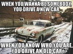 an old car parked on the side of a snow covered road next to a brick building